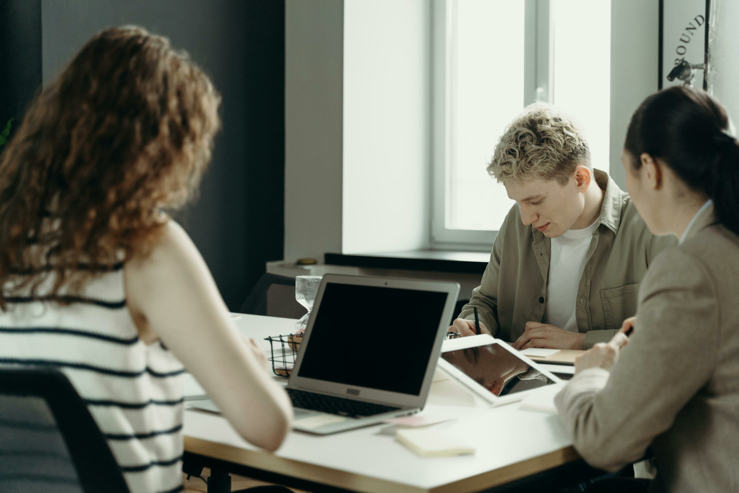 three people working on laptops in an office